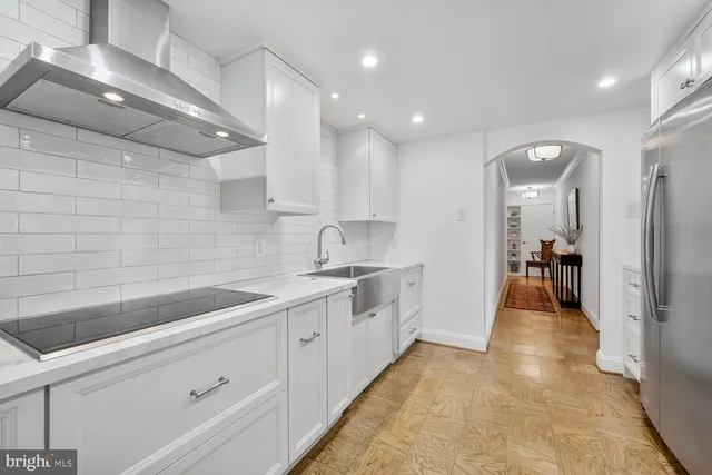 a large white kitchen with stainless steel appliances granite countertop a sink and cabinets