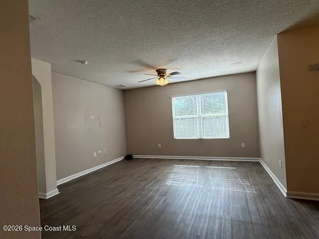 an empty room with wooden floor fireplace and staircase