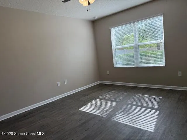 an empty room with wooden floor cabinet and windows