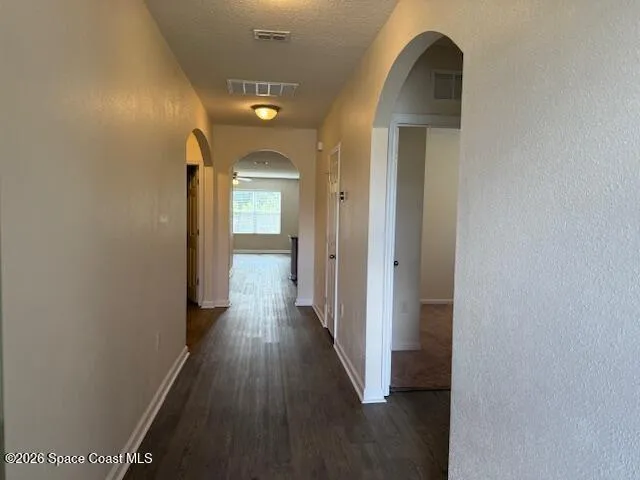 a view of a hallway with wooden floor and a bathroom