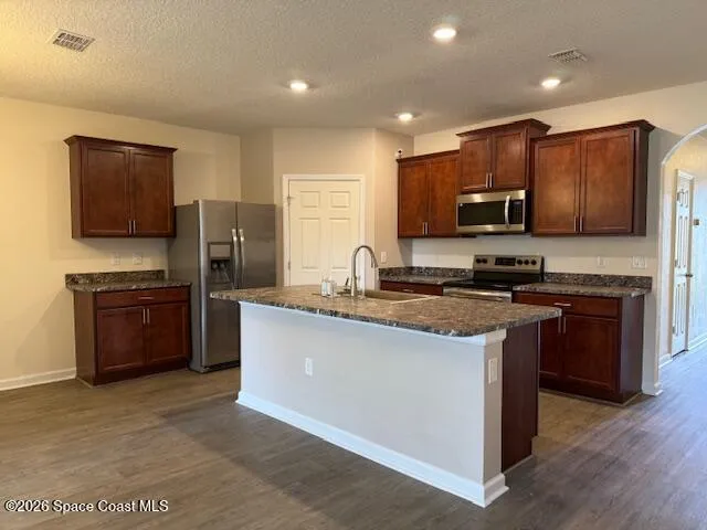 a kitchen with stainless steel appliances wooden cabinets a stove a microwave a sink and a refrigerator