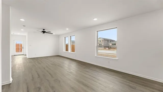 a view of an empty room with a window and wooden floor