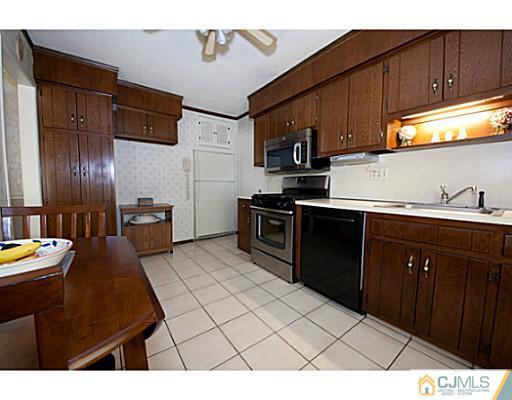 29 Orchard Road Middlesex, NJ 08846 - Photo 4 of 25 a kitchen with stainless steel appliances kitchen island granite countertop a sink dishwasher stove and refrigerator with wooden cabinets