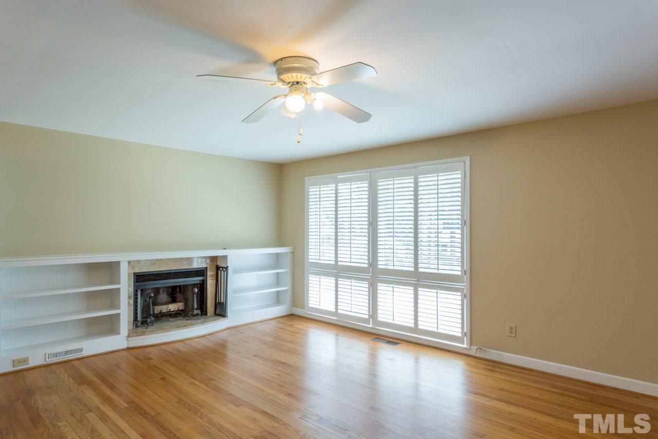 3408 Cherry Lane Raleigh, NC 27607 - Photo 3 of 25 an empty room with wooden floor fireplace and windows