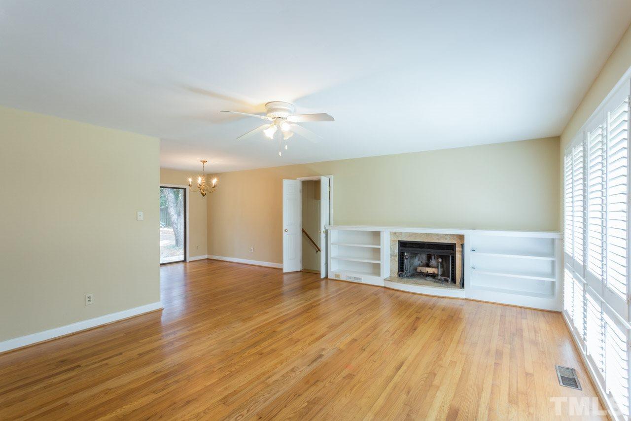 3408 Cherry Lane Raleigh, NC 27607 - Photo 5 of 25 an empty room with wooden floor fireplace and windows