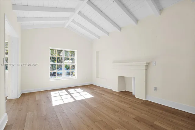 an empty room with wooden floor chandelier and windows