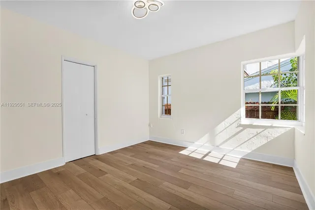 a view of empty room with wooden floor and fan