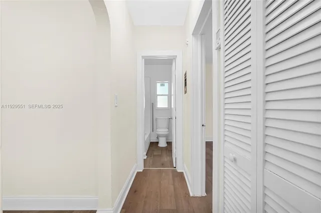 a view of a hallway with wooden floor and a bathroom