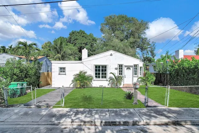 a front view of a house with a yard and trees