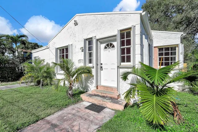 a backyard of a house with plants and large tree
