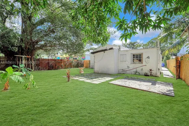 a backyard of a house with plants and large tree