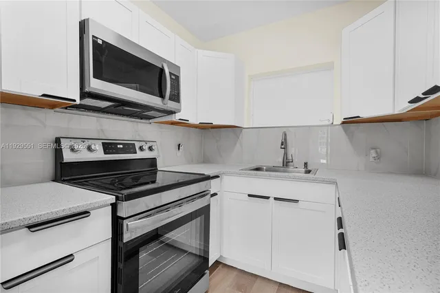 a kitchen with cabinets stove and microwave