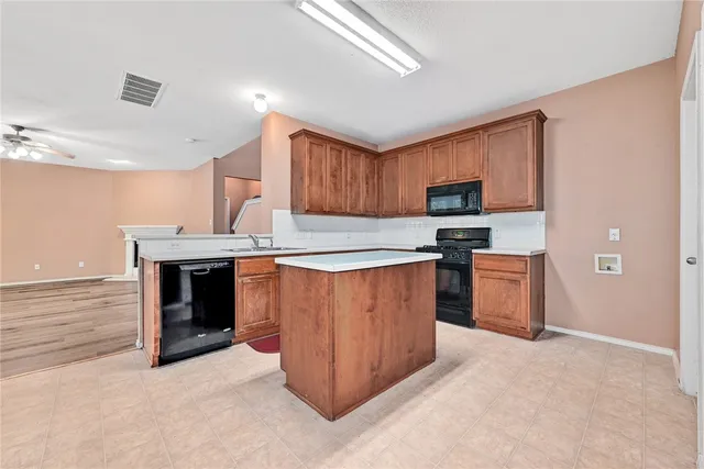 a kitchen with stainless steel appliances granite countertop a stove top oven a sink dishwasher and a refrigerator with wooden cabinets