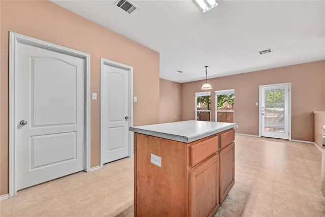 an empty room with kitchen view and wooden floor