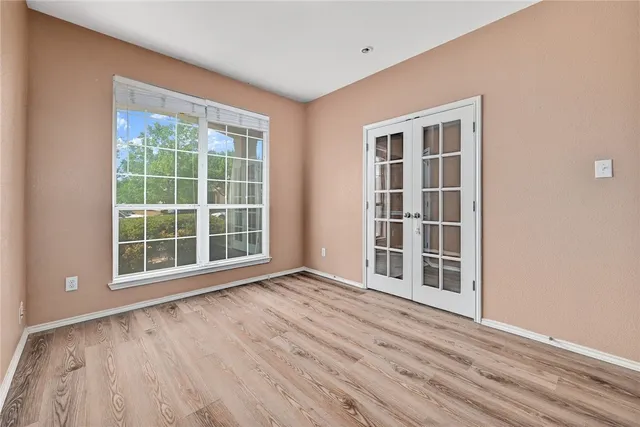 a view of empty room with wooden floor and windows