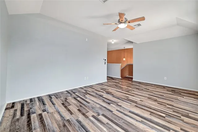 a view of a room with a ceiling fan and wooden floor