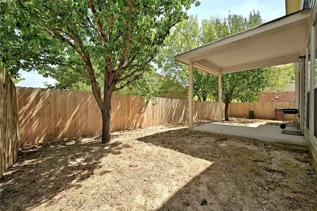 a backyard of a house with a large tree and wooden fence