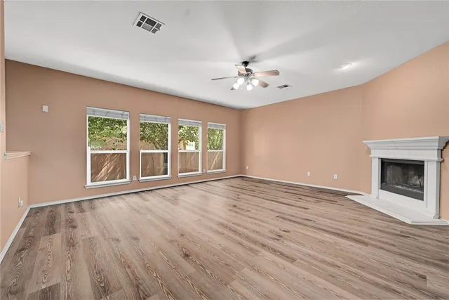 a view of an empty room with a window and wooden floor