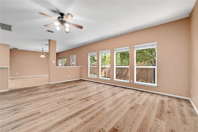 a view of an empty room with a window and wooden floor