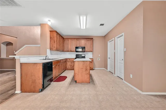 a kitchen with stainless steel appliances granite countertop a stove top oven a sink and a refrigerator