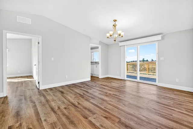 a view of an empty room with window and wooden floor
