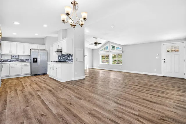 a view of an empty room with a window and a kitchen