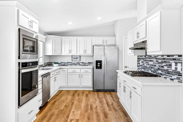 a kitchen with white cabinets and stainless steel appliances