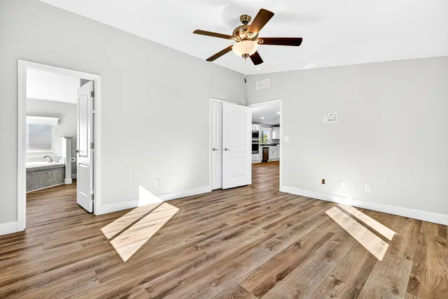 an empty room with wooden floor and ceiling fan