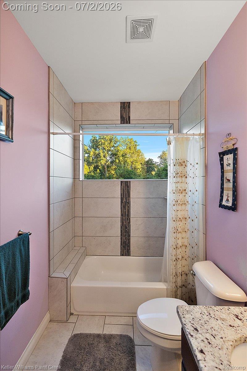 54230 Card Road Macomb, MI 48042 - Photo 63 of 73 Bathroom featuring a window above the tub, tiled shower surround with a decorative vertical accent, built-in shower bench, and a vanity with a stone-finish countertop