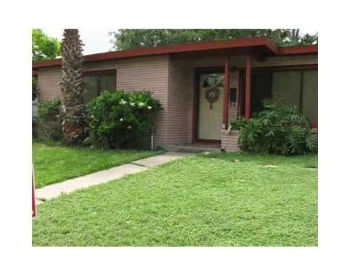 a view of a house with brick walls and a yard with potted plants