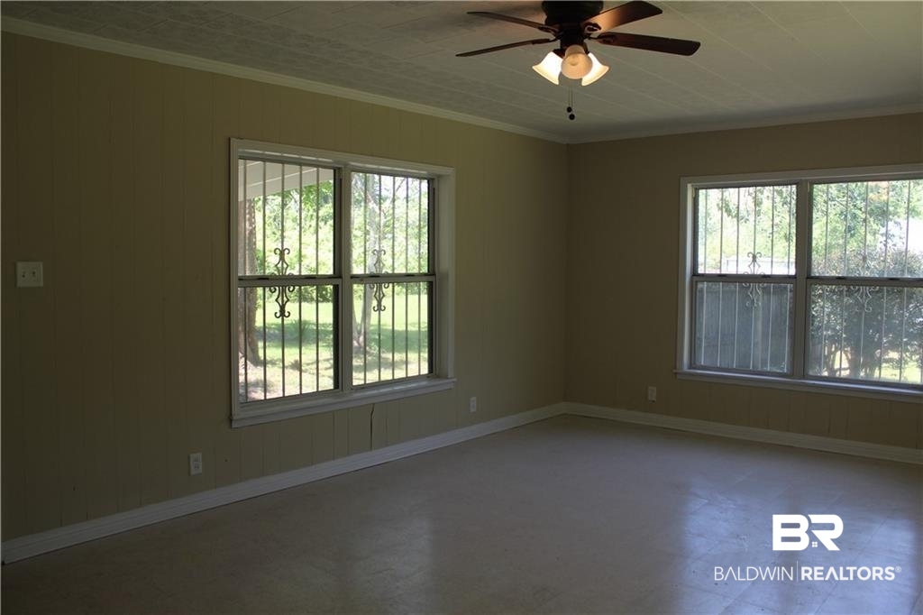 5710 Antoine Road Mobile, AL 36693 - Photo 6 of 7 Unfurnished room featuring a ceiling fan, crown molding, and wooden walls