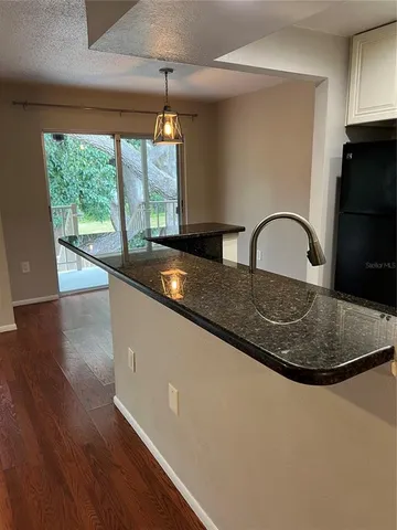 a kitchen with granite countertop a stove a sink and a dining table with wooden floor