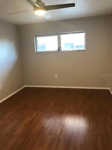 a view of an empty room with wooden floor and a window