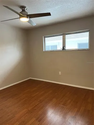 a view of an empty room with wooden floor fan