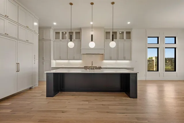 a large kitchen with stainless steel appliances kitchen island granite countertop a stove a sink a refrigerator and a wooden floors