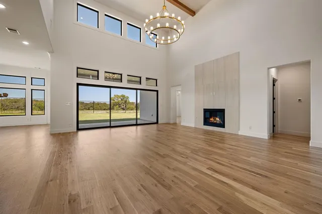 a view of an empty room with wooden floor and a fireplace