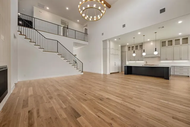a view of an empty room with wooden floor and a chandelier