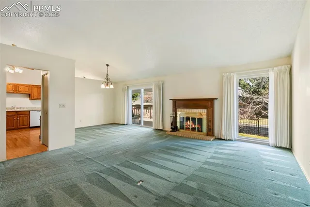 a view of an empty room with wooden floor fireplace and a window