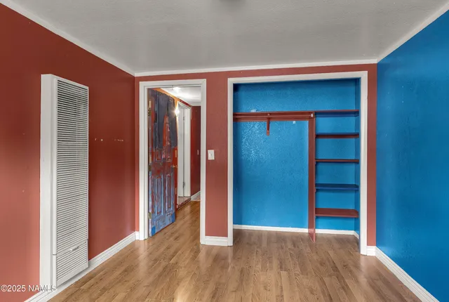 a view of an empty room with wooden floor and closet