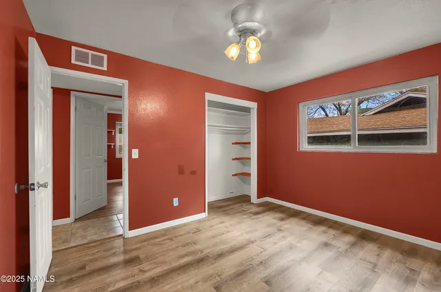 an empty room with a chandelier fan and windows