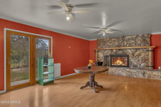 a view of a livingroom with a fireplace a ceiling fan and windows