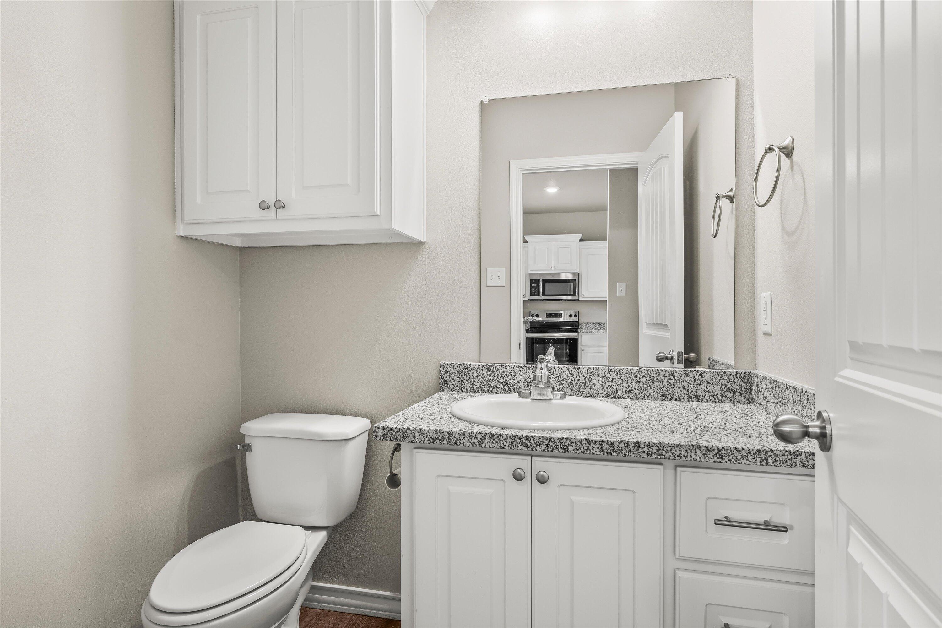 6040 24th Street, Unit 10 Lubbock, TX 79407 - Photo 15 of 29 a bathroom with a granite countertop toilet sink and mirror