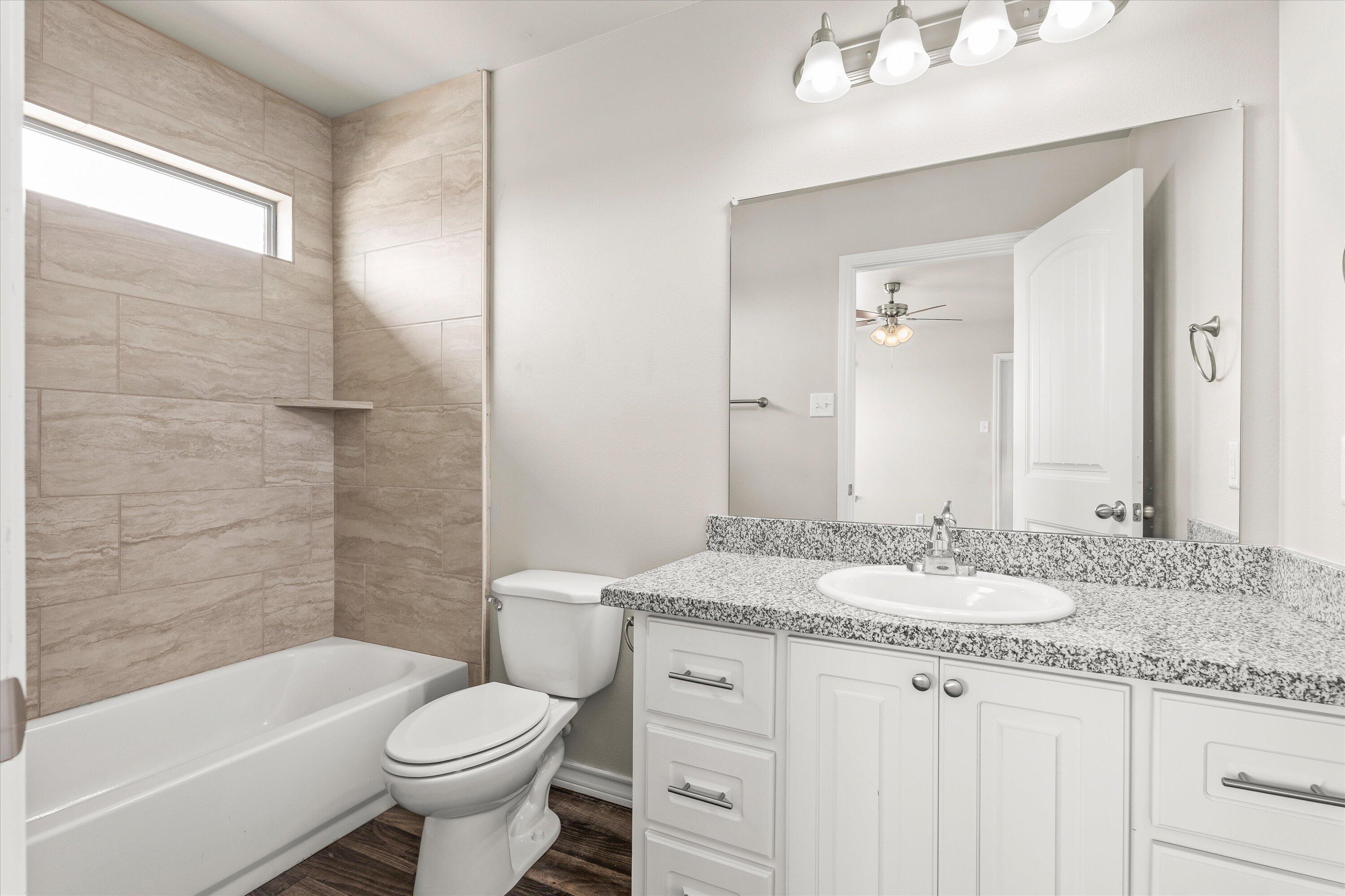 6040 24th Street, Unit 10 Lubbock, TX 79407 - Photo 22 of 29 a bathroom with a granite countertop sink toilet mirror and bathtub
