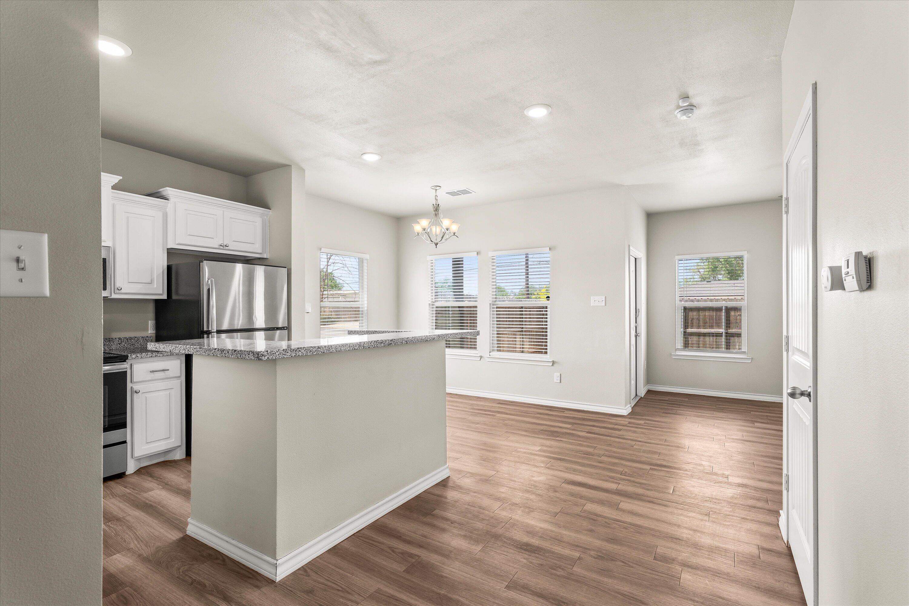 6040 24th Street, Unit 10 Lubbock, TX 79407 - Photo 9 of 29 a kitchen with stainless steel appliances kitchen island wooden cabinets and granite counter tops