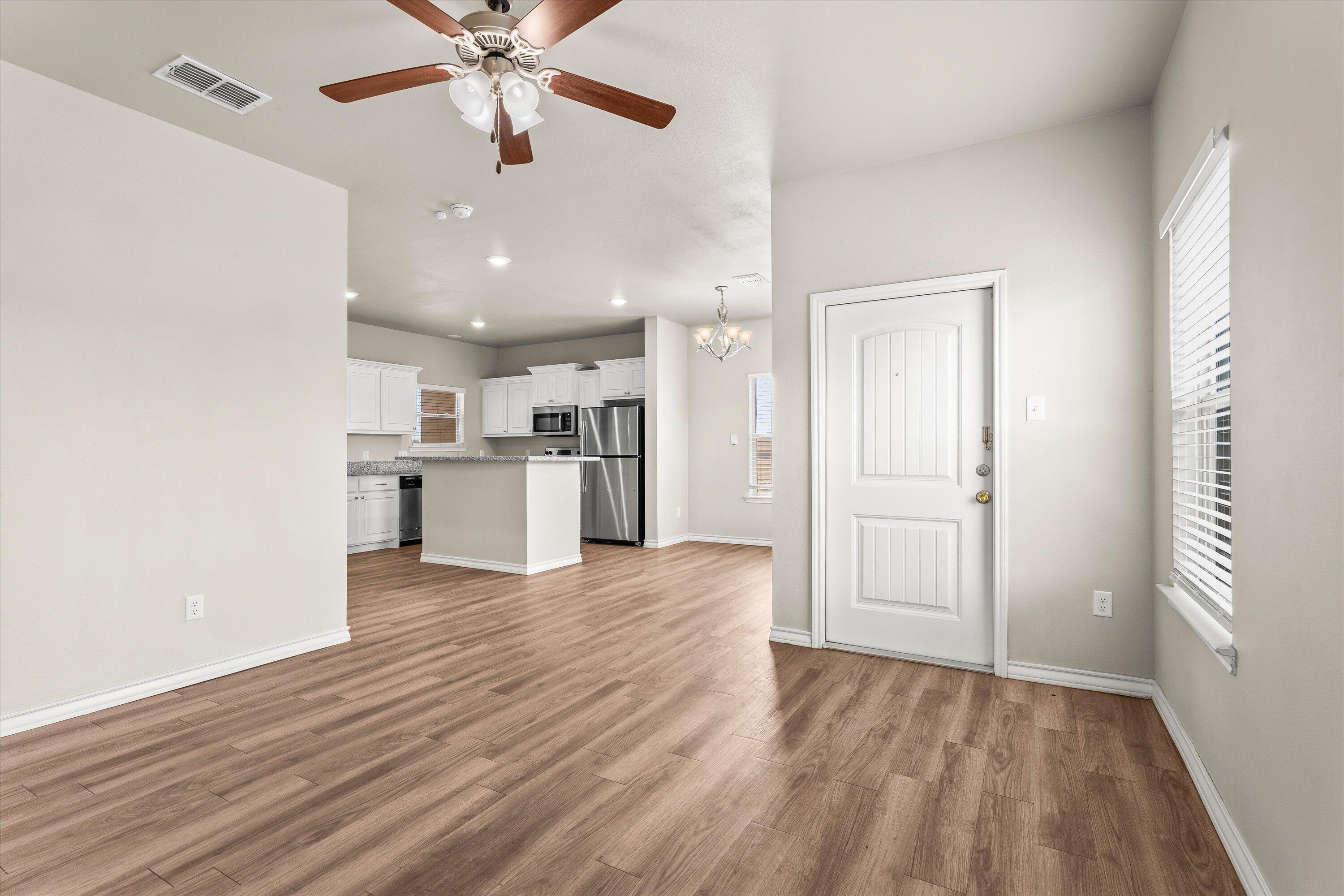 6040 24th Street, Unit 10 Lubbock, TX 79407 - Photo 10 of 29 a view of a kitchen with wooden floor and a ceiling fan
