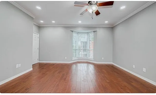 a view of an empty room with wooden floor and windows