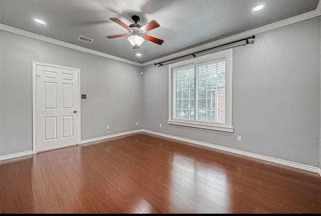 a view of an empty room with a window and wooden floor