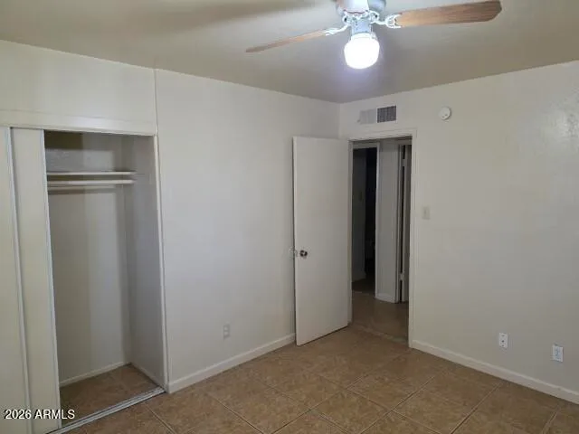 an empty room with a chandelier fan and windows
