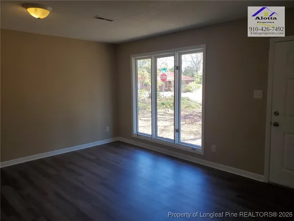 an empty room with wooden floor and windows