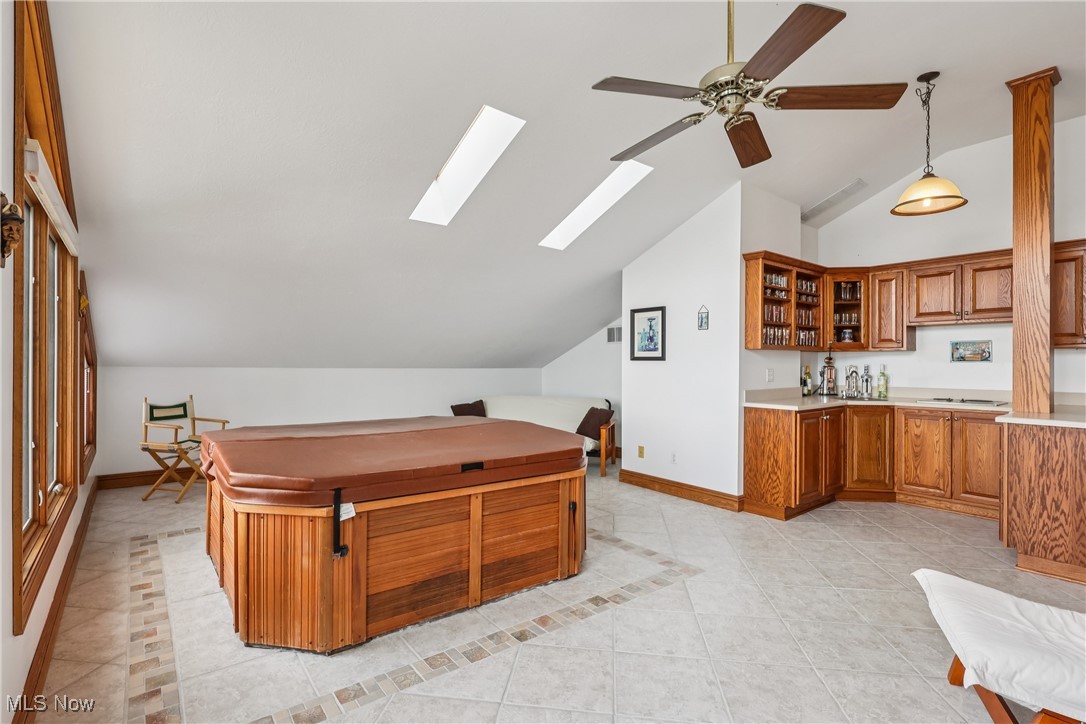 337 Cedar Point Road Sandusky, OH 44870 - Photo 30 of 50 Kitchen with vaulted ceiling, brown cabinetry, glass insert cabinets, light countertops, and light tile patterned floors